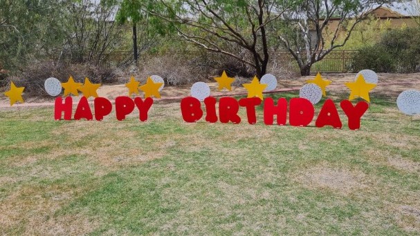 big red Happy Birthday letters with stars and golf balls in yard