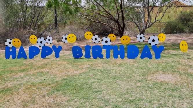 big blue Happy Birthday yard letters with smileys and soccer balls