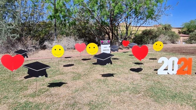 yard sign display of graduation caps, hearts, 2021 and smiley faces near Carefree